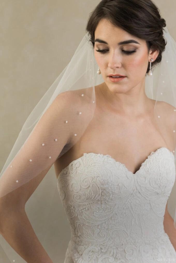 Model wearing Lii Bridal accessories that include a veil and earrings