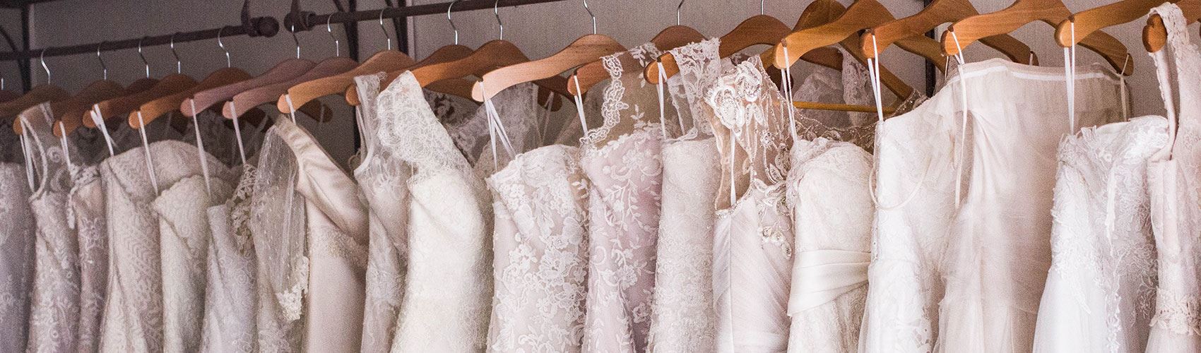 Pink tinted wedding dresses on rack. Desktop Image.