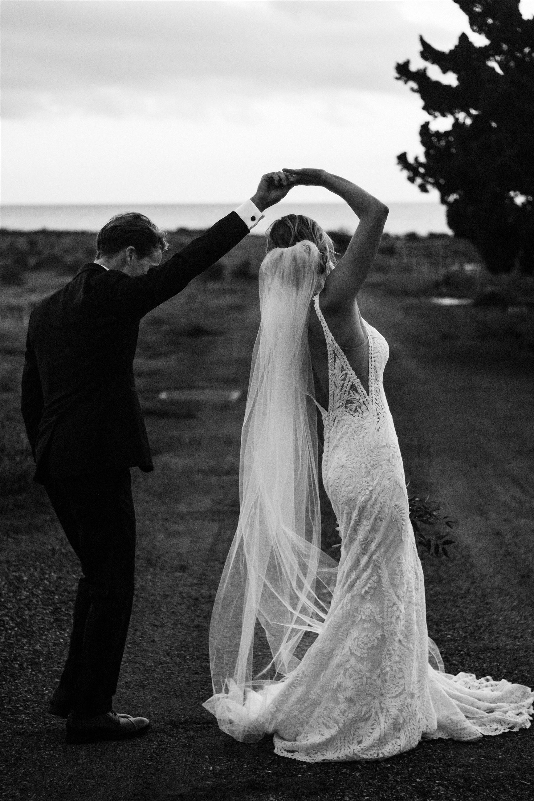Black and White Photo Of Bride And Groom Dancing In Field.