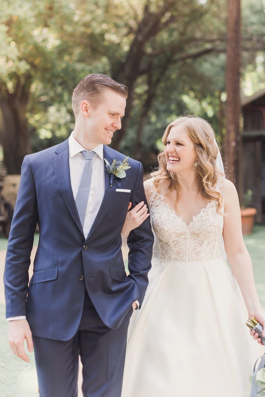 Bride And Groom Walking In Front Of Trees.