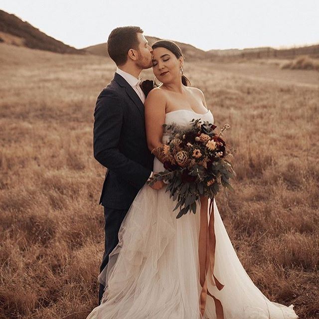 Bride In Strapless White Wedding Dress Holding Boutique And Being Kissed By Groom